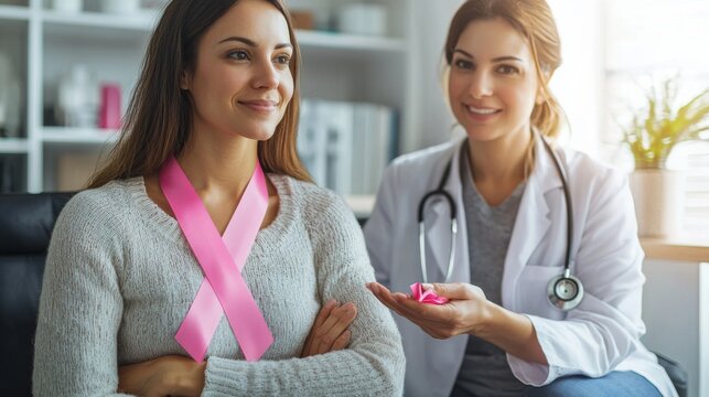 A woman holding a pink ribbon while sitting with a medical professional - Powered by Adobe