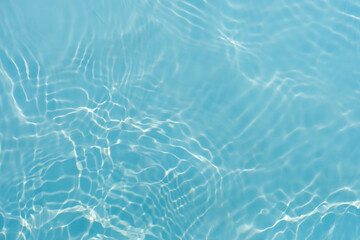 Blue water with ripples on the surface. Defocus blurred transparent blue colored clear calm water surface texture with splashes and bubbles. Water waves with shining pattern texture background.