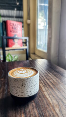 a cup of coffee on the table with a blurred bookshelf background