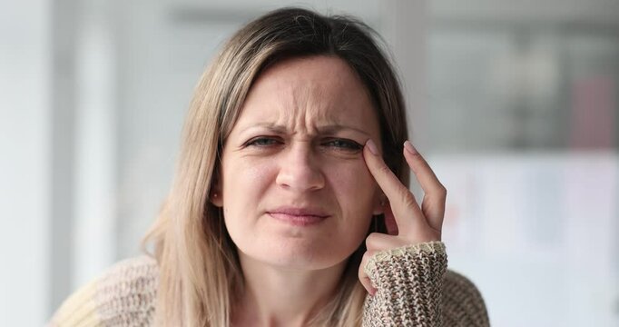 Young woman with poor eyesight squints and pulls eyelids to sides with hands