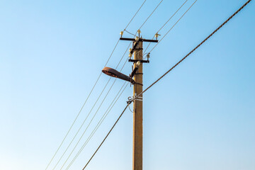Fototapeta premium Power lines on the background of the blue sky close-up. Electric hub on a pole. High voltage wires in the sky. Emergency lights out. Destruction of the energy system of Ukraine
