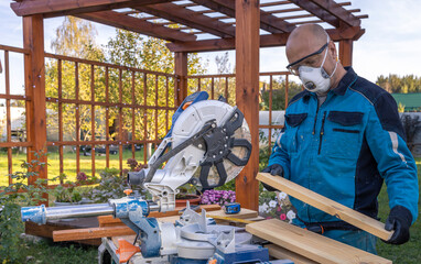 A man wearing a mask is cutting wood with a saw