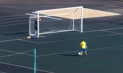 Obraz premium A boy in a yellow shirt is playing soccer on a field