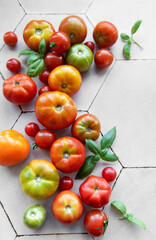 Freshly harvested tomatoes and basil scattered on a hexagonal tile kitchen surface during summer