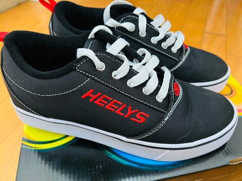 New pair of Heelys brand shoes with a wheel on the bottom of the sole.