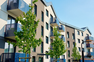 Modern apartment building with balconies and green trees on sunny day. Residential complex in Wroclaw, Poland. Mortgage in real estate