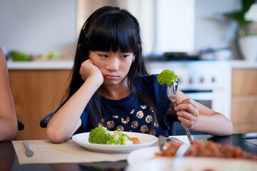Food, unhappy and child with broccoli in kitchen for healthy meal, nutrition or problem with...
