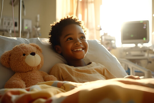 A black kid smiling on a bed in a hospital