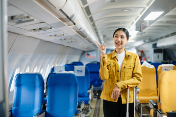 Attractive Asian female passenger of airplane sitting in comfortable seat while working laptop and tablet. Travel in style, work with grace.