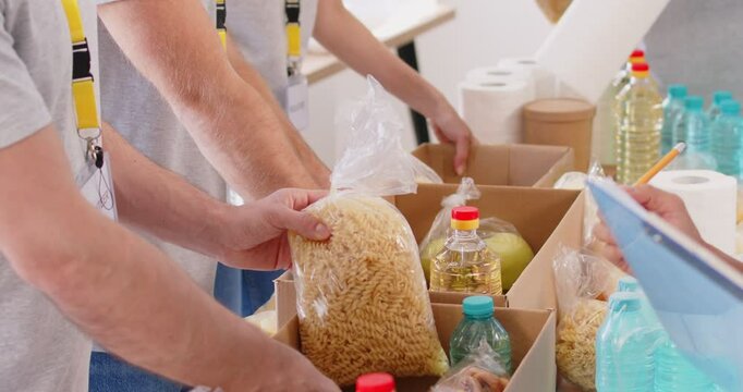 Close up shot of a volunteer team hands packing food into boxes at a humanitarian center. Teamwork, dedication to charity, and support for humanitarian efforts through food donation.