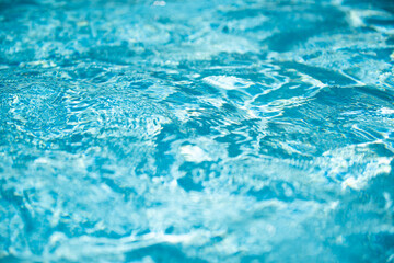 Blue pool water background. Blurred transparent clear calm water surface texture. Water waves in sunlight with copy space.
