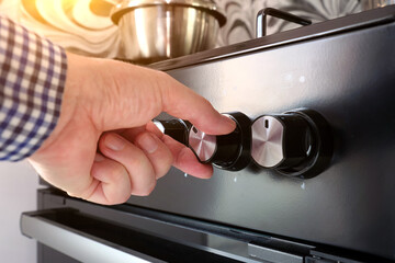Close-up a man hand turns on a gas stove to cook food in the home.