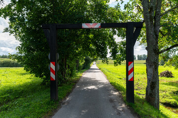 A picturesque rural path framed by a wooden gateway under a clear sky on a sunny day