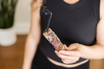 Close up of woman's hand holding a burning sage smude stick