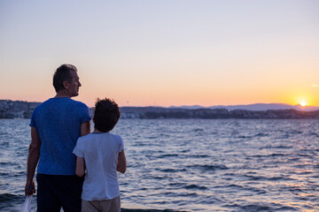 Fototapeta premium Father and son are watching beautiful sunset by the sea