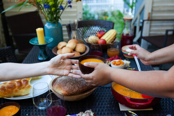 a black woman passes soup to a white woman over a fall feast