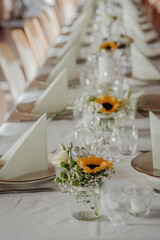 Wedding table with sunflower and rose centerpieces in rustic style