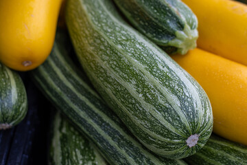 Close-up of striped green zucchini and yellow squash piled together