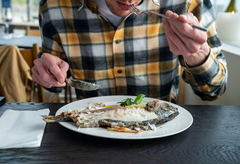 close up of man eating cooked fish in restaurant