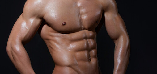 Fototapeta premium Cropped image of fit man showing six pack abs. Perfect abs, shoulders, and chest. Close up the Abs. Closeup torso. Ab. Muscular torso and ripped abs. Sexy male muscular body.
