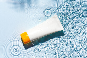 Tropical setting with a skincare tube resting on textured white surface illuminated by sunlight