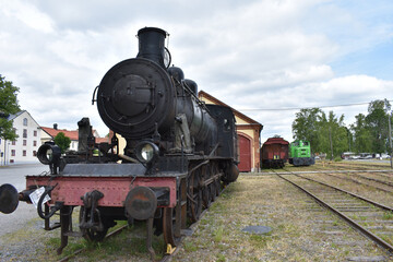 Alte Dampflok vor Lokschuppen mit Waggons in Nora