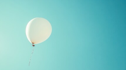 White balloon floating upwards into a clear blue sky symbolizing freedom and letting go as it drifts higher