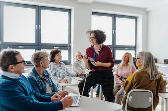 Teacher explaining senior students how to start their own business. Elderly people attending computer and technology education class. Entrepreneurship program for seniors.