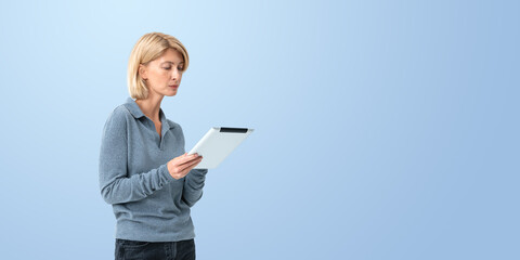 Serious woman looking at tablet in hands, copy space background