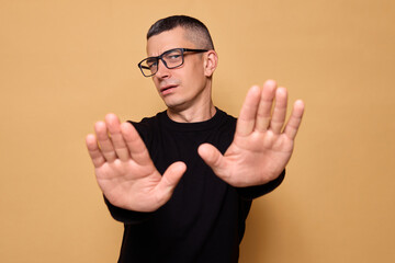 Upset male in black jumper and glasses demonstrating warning sign indicating forbidden action and...