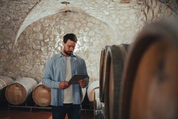 The winemaker standing in the wine cellar, monitoring the fermentation and aging processes in large...