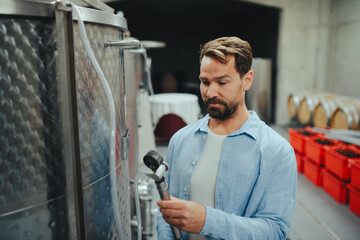 Winemaker standing in the wine cellar, controlling pressure in fermentation tank.