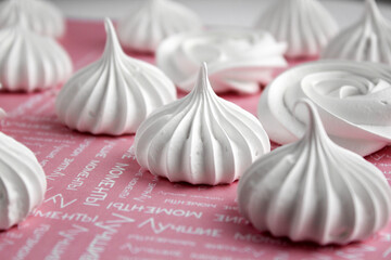 Delicious snow-white meringue embedded in a row on a pink background. A poster for a cafe, pastry shop, bakery. Dessert advertising
