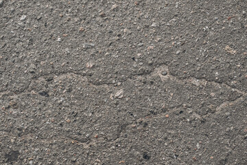 Cracked asphalt pavement with a rough texture in a city setting during daylight hours