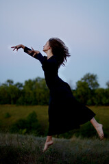 young girl dancing in a black dress like a witch for Halloween