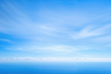 Fototapeta premium Wispy clouds on blue sky over ocean