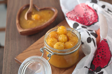 Glass jar of apple jam on wooden olive board. Home made fruit from garden. Kitchen interior and organic food. 