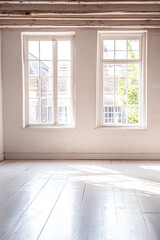 Fototapeta premium Bright and airy empty room with natural light streaming through large windows in a historic building