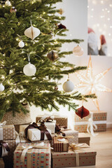Christmas tree in stylish winter holiday interior with stars, lights, gifts and decoration closeup detail. Xmas interior design template
