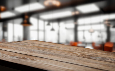 Empty wooden table top in a blurry modern restaurant setting.