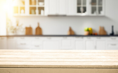 Empty wooden countertop in a bright kitchen with white cabinets and sunbeams.