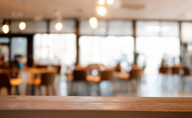 A wooden table top with a blurred background of a modern cafe. The perfect place to set down a cup of coffee or a plate of food.