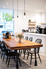 Warm and inviting cafe interior with a large wooden table surrounded by black chairs, decorated with flowers