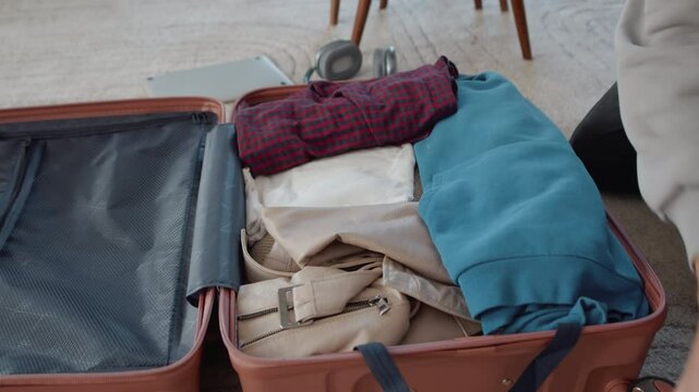 Traveler arranging clothes inside suitcase