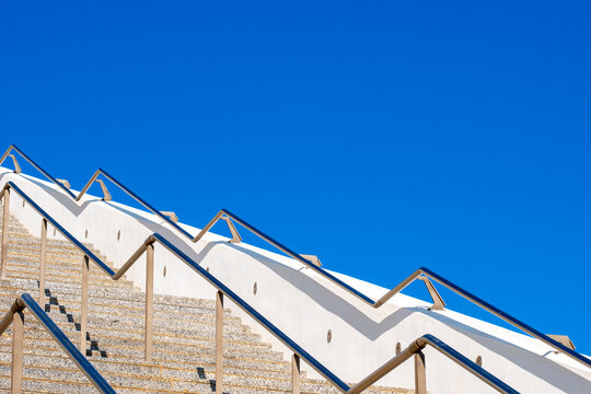 A modern outdoor staircase with sleek railings ascending under a vibrant blue sky demonstrating architectural beauty and clear weather conditions.