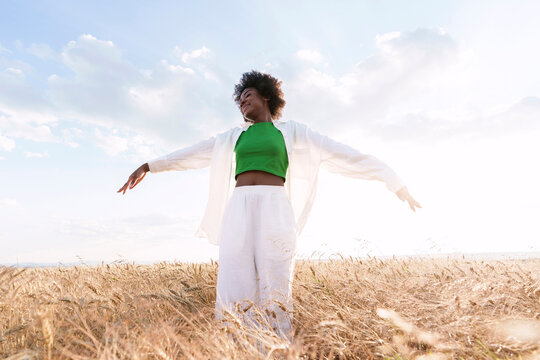 Carefree woman standing amidst plants in field