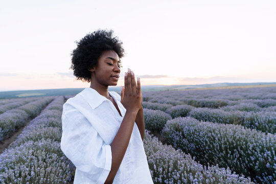 Young woman with prayer pose standing in lavender field