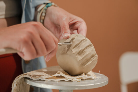 Potter shaping clay ceramic bowl with tool at workshop