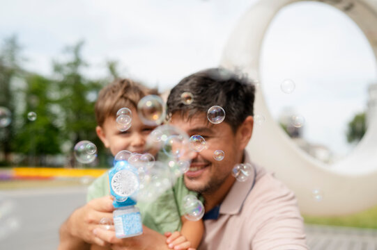 Father and son playing with bubble gun at park