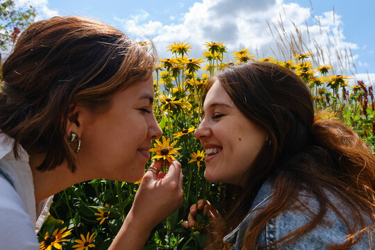 Happy gay couple smelling conflower in garden